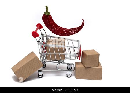 Primo piano di un piccolo carrello in metallo con diversi pacchetti all'interno e accanto ad esso e asciugato su baccello rosso peperoncino cialda sopra su sfondo bianco Foto Stock