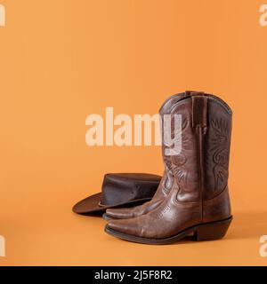 Stivali e cappello del cowboy americano selvaggio occidentale del texas come minimo concetto creativo e rodeo rurale e simbolo della fattoria. Foto Stock