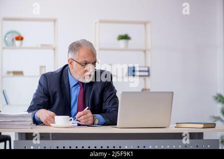 Vecchio dipendente di un uomo d'affari che lavora sul posto di lavoro Foto Stock