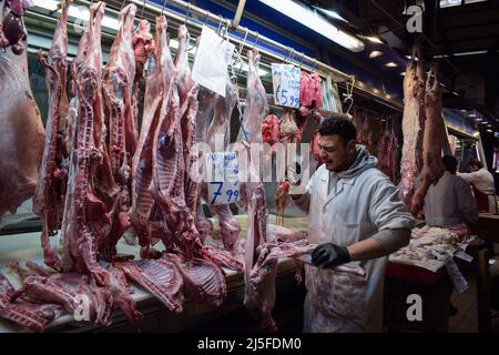 Atene, Grecia. 21st Apr 2022. Un macellaio è visto tagliare la carne in pezzi più piccoli come agnelli macellati interi e capre sono appesi pronti per la vendita nel famoso mercato alimentare di Varvakios per il tradizionale pasto pasquale spit-arrostito. L'aumento dei prezzi ha colpito la delicatezza tradizionale greca preferita. (Foto di Dimitris Aspiotis/Pacific Press) Credit: Pacific Press Media Production Corp./Alamy Live News Foto Stock