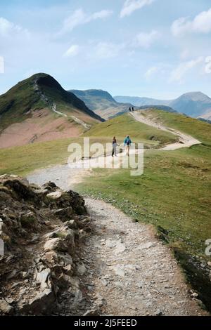 Camminatori camminano lungo un percorso verso la cima di Cat Bells nel Lake District inglese alto sopra Derwent acqua nei laghi nord-ovest in una giornata limpida. Foto Stock