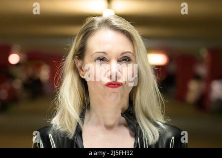 Primo piano ritratto di bella giovane donna con capelli biondi indossare giacca in pelle puckering labbra al garage parcheggio Foto Stock