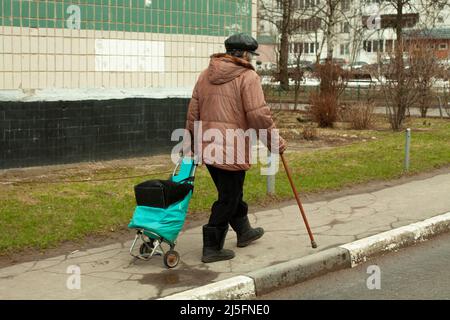 Pensionato in Russia. Una donna anziana cammina lungo la strada appoggiandosi su un bastone per facilitare la camminata. Un vecchio a Mosca. Foto Stock