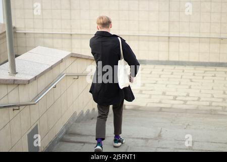 Il ragazzo sta scendendo le scale. Attraversamento pedonale. Un uomo va al lavoro. Un abitante della città sulla strada. Foto Stock