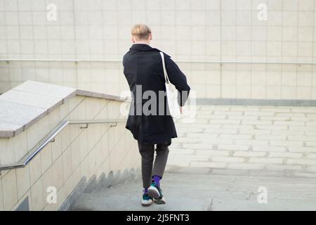 Il ragazzo sta scendendo le scale. Attraversamento pedonale. Un uomo va al lavoro. Un abitante della città sulla strada. Foto Stock