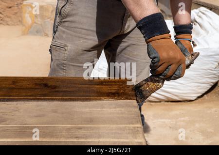 Uomo che lavora al restauro di mobili antichi utilizzando bitume judaicum. Cura del legno e concetto di impermeabilizzazione Foto Stock