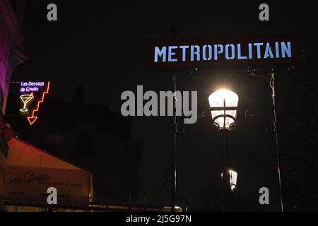 Parigi, Francia: Vista notturna, lampioni di strada e segni al neon all'ingresso della stazione della metropolitana di Montmartre, famosa collina nel nord 18th ° arrondissement Foto Stock