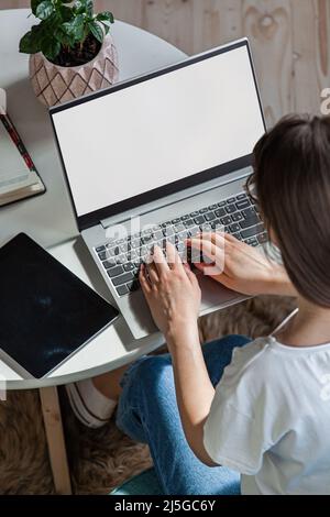 Giovane donna che usa lo schermo del laptop vuoto, mock-up, lavoro a casa, vista dall'alto Foto Stock