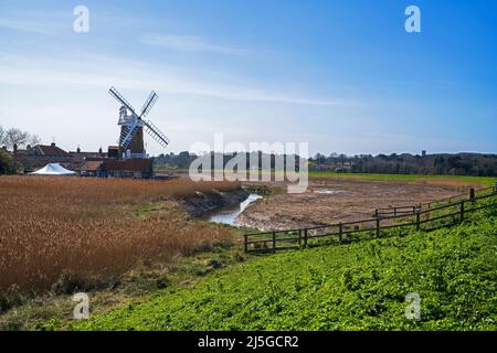 Una vista del mulino a vento di Cley con il fiume Glaven che scorre attraverso i letti di canna sulla costa nord del Norfolk a Cley-next-the-Sea, Norfolk, Inghilterra, Regno Unito Foto Stock