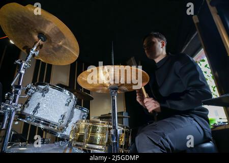 Il batterista si siede al drum set e gioca. Tiene i bastoncini nelle sue mani Foto Stock