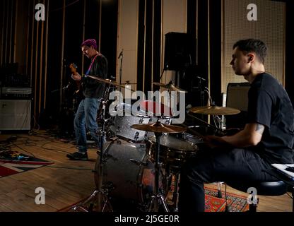 Il batterista si siede al drum set e gioca. Tiene i bastoncini nelle sue mani Foto Stock