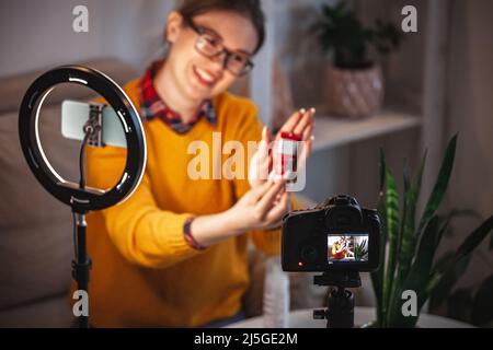 Donna di bellezza blogger fa video revisione di cosmetici a casa Foto Stock