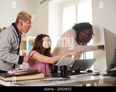 team di fotografi che lavorano con un computer portatile sul posto di lavoro con due computer in studio Foto Stock