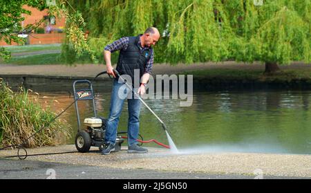 Lavaggio a getto d'uomo zona lastricata lungo il fiume. Foto Stock