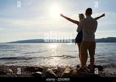 Uomo in piedi dietro e tenendo la ragazza con le braccia allungate Foto Stock