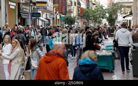 Palma, Spagna. 23rd Apr 2022. Passers-by curiosa tra i libri in una bancarella su Sant Miquel Street il giorno di San Giorgio (George's Day). Il 23 aprile si celebra la Giornata Mondiale del Libro, e a Maiorca è tipico che le biblioteche allestano le loro bancarelle nelle strade principali. Credit: Clara Margais/dpa/Alamy Live News Foto Stock