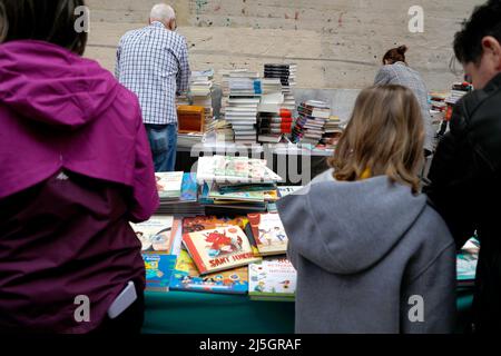 Palma, Spagna. 23rd Apr 2022. Passers-by curiosa tra i libri in una bancarella su Sant Miquel Street il giorno di San Giorgio (George's Day). Il 23 aprile si celebra la Giornata Mondiale del Libro, e a Maiorca è tipico che le biblioteche allestano le loro bancarelle nelle strade principali. Credit: Clara Margais/dpa/Alamy Live News Foto Stock