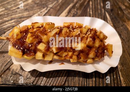 Hotdog in stile coreano, cibo di strada coreano, hotdog con patate fritte, su tavola di legno. Foto Stock