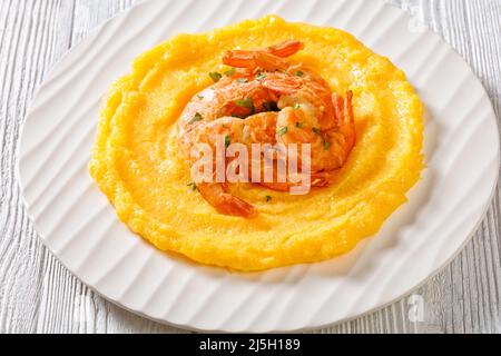 Polenta e schie fritte, piatto veneziano, polenta con gamberi fritti su piatto bianco su tavola in legno testurizzato, vista orizzontale dall'alto, primo piano Foto Stock