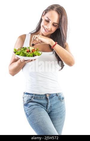 Una donna di buon aspetto che tiene una ciotola di insalata fresca, degustando un'oliva nera. Isolato su bianco. Foto Stock