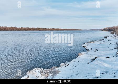 Paesaggio primaverile sul fiume, Russia. Neve sciolta e ghiacci grigi sulla riva. Foto Stock