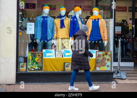 Sostegno all'Ucraina. Una vetrina con abiti gialli e blu su manichini e quadri di girasoli. Display a colori Foto Stock