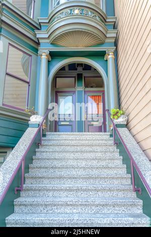 Esterno della casa cittadina in stile vittoriano con scale in cemento e corrimano in metallo a San Francisco. Scala che conduce al portico con entra ad arco Foto Stock