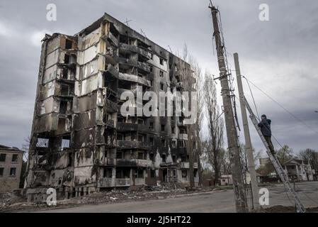 Borodyanka, Ucraina. 23rd Apr 2022. Un riparatore lavora su un palo vicino a edifici danneggiati dopo scioperi missilistici a Borodyana, Ukriane, sabato 23 aprile 2022. Un'evacuazione pianificata di civili nella città meridionale assediata di Mariupol sabato è stata nuovamente ostacolata dall'esercito russo, secondo i leader ucraini. Foto di Ken Cedeno/UPI Credit: UPI/Alamy Live News Foto Stock