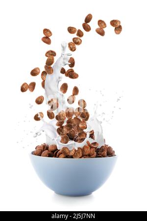 Versare in una ciotola gustosi fiocchi di mais al cioccolato con spruzzi di latte su sfondo bianco Foto Stock