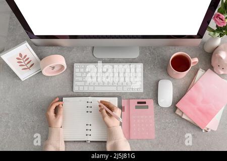 Donna che fa note in notebook sul tavolo Foto Stock