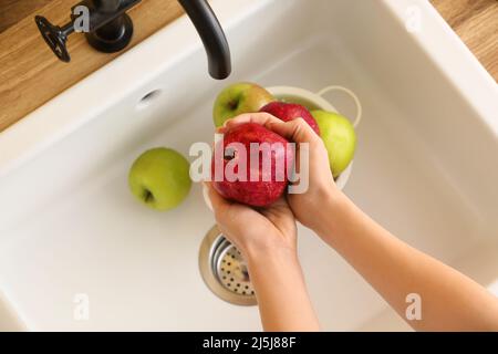 Donna che lava melograno maturo nel lavandino, primo piano Foto Stock