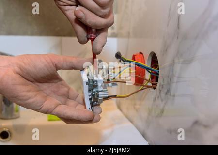Elettricista nel montaggio delle prese elettriche a parete Foto Stock