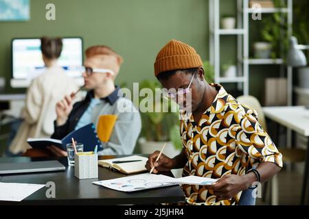 Vista laterale ritratto di creativo afroamericano uomo analisi dati rapporto in business meeting, spazio copia Foto Stock