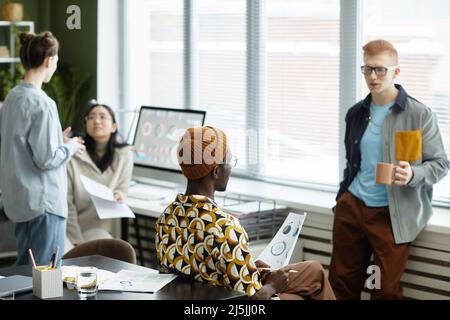 Ritratto di due giovani uomini che discutono di lavoro in ufficio durante la pausa caffè Foto Stock