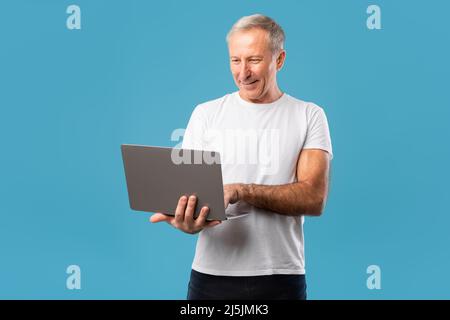 Uomo maturo sicuro che tiene e utilizza il notebook Foto Stock