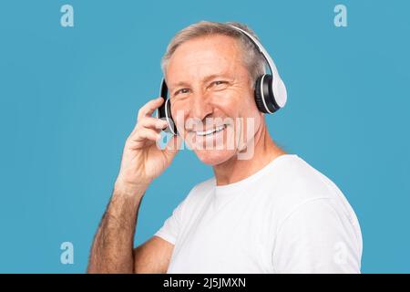 Headshot Ritratto di un uomo maturo eccitato che indossa cuffie wireless Foto Stock