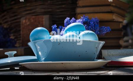 Uova blu in una pentola di ghisa con libri antichi sullo sfondo. Umore di Pasqua. Foto Stock