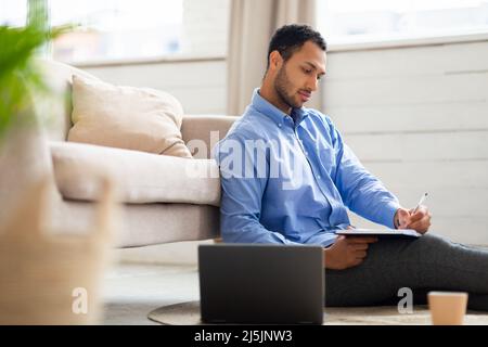 Ritratto del giovane uomo arabo con computer portatile e scrittura Foto Stock