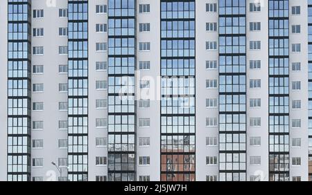 Vista frontale del nuovo e alto edificio residenziale con molte finestre durante la giornata invernale Foto Stock