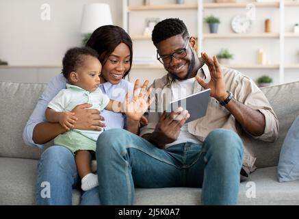 Una famiglia allegra di colore nero che ha una videocamera con le mani che ondano sul tablet Foto Stock