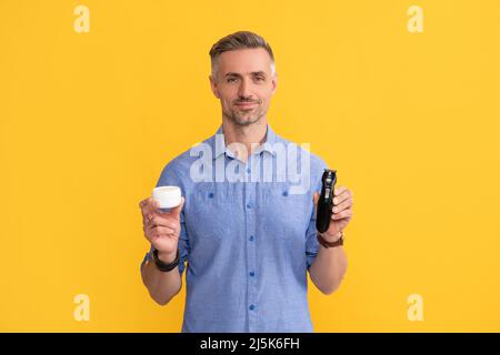 bellezza uomo. barbiere. dopo la rasatura. uomo che tiene rasoio elettrico e crema. Foto Stock