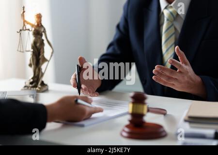 Donna d'affari e avvocati discutere di documenti contrattuali con scala di ottone su scrivania in legno in ufficio. Diritto, servizi legali, consulenza, concetto di giustizia. Foto Stock