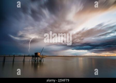 Drammatico tempesta nuvole e mare calmo al tramonto costa atlantica occidentale Francia estuario Gironde, Charente Maritime con fulmini sciopero all'orizzonte dell'oceano Foto Stock