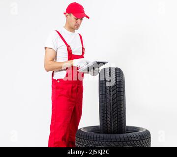 Giovane meccanico in uniforme con un portadocumenti su sfondo bianco Foto Stock