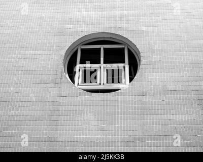 Vecchia finestra rotonda su un edificio bianco pulito all'aperto con pareti a mosaico, vista dall'esterno, stile minimale. Foto Stock