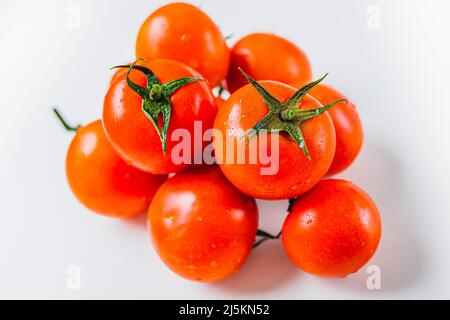 Mazzo di pomodori maturi con una fonte di luce naturale. Pomodori maturi sulla vite. Pomodori rossi maturi in gocce d'acqua Foto Stock