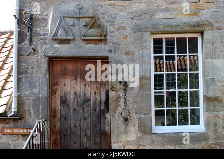 Ceres, Fife, Scotland, UK. Situato in una piccola glen, a circa 2 miglia sopra il Ceres Moor da Cupar e a 7 miglia da St Andrews. L'ex parrocchia di questo nome includeva gli insediamenti di Baldinnie, Chance Inn, Craigrothie, Pitscottie e Tarvit Mill. E' anche la sede del Museo Folcloristico di Fife. Scultura in pietra di scale sopra la porta della Weigh House ex Barons Court. L'iscrizione dice che Dio benedica il giusto Foto Stock