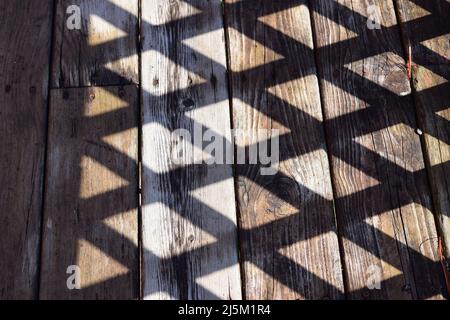 Ombra colta da traliccio di legno su un ponte di legno Foto Stock