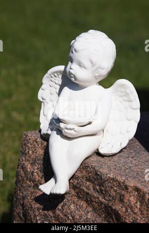 Primo piano di una figurina di Angelo in cima a una lapide in un cimitero. Foto Stock