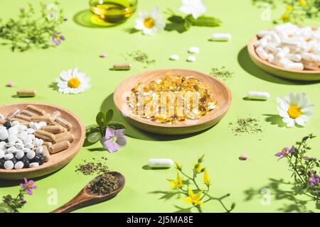 Diverse capsule vitaminiche e integratori dietetici su sfondo verde. Concetto di complessi vitaminici. Foto Stock